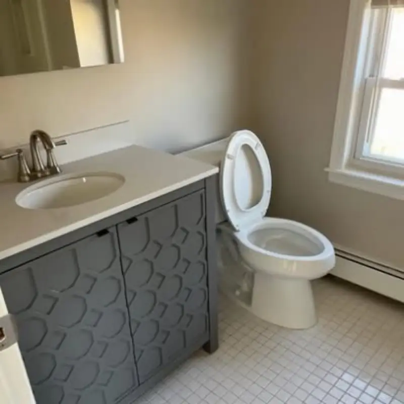A clean bathroom vanity, sink and toilet on a white tile floor