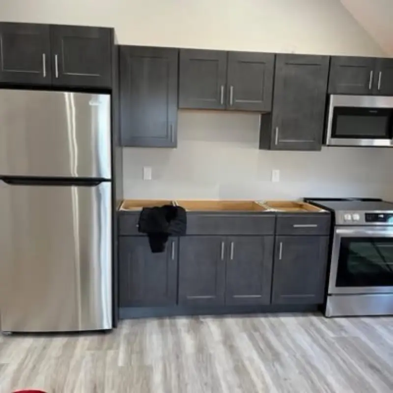 An empty kitchen with dark shaker cabinets and stainless appliances, cleaned for a move-in
