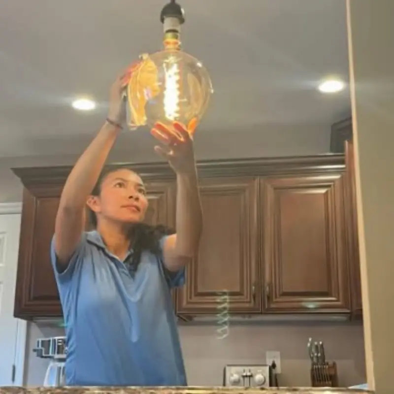 A Dust Buster cleaner wiping a filament pendant bulb above a kitchen counter
