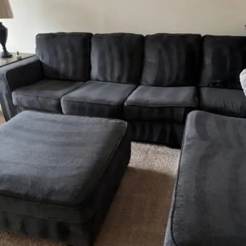 A dark sectional sofa and ottomans on a carpeted living room floor