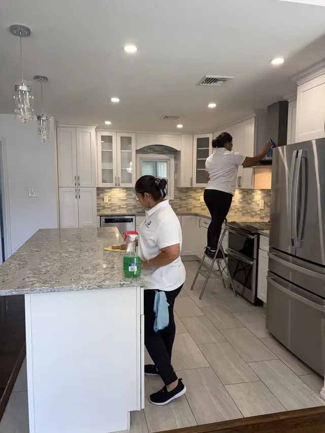 Two Dust Buster cleaners working in a bright white shaker kitchen